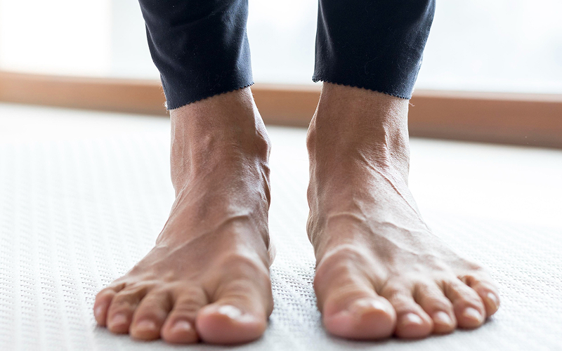 Close-up of a person's bare flat feet standing on a mat.
