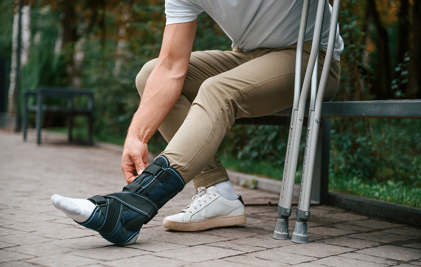 Injured man adjusting supportive brace on his outer ankle.