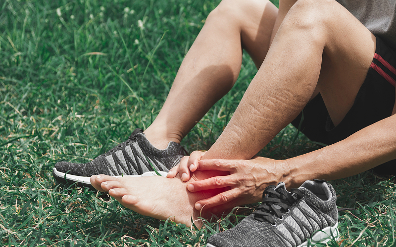 Athlete sitting on grass clutching a painful ATFL tear injury.