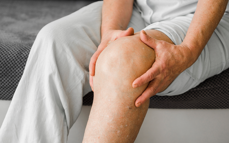 Person holding a painful, swollen knee with knee bursitis.