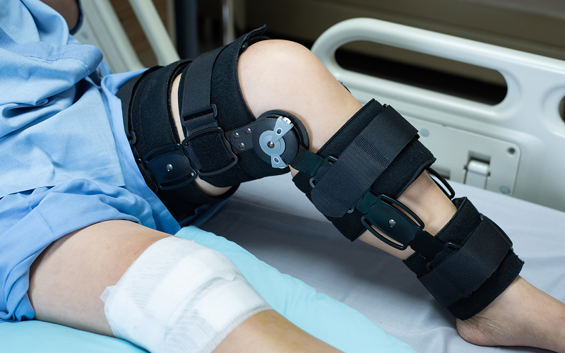 Patient wearing knee brace recovering from meniscus tear surgery.