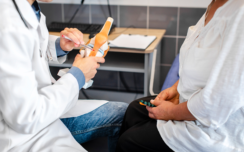 Orthopedic specialist explaining tendon conditions using an anatomical model.