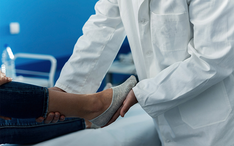 Orthopedic specialist examining patient foot and heel during clinical consultation.