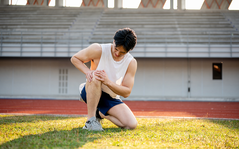 Athlete clutching knee in pain from meniscus or MCL tear.
